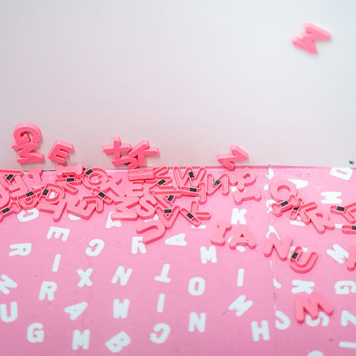 Aimants de lettre rose sur un papier rose avec motif de lettres blanches